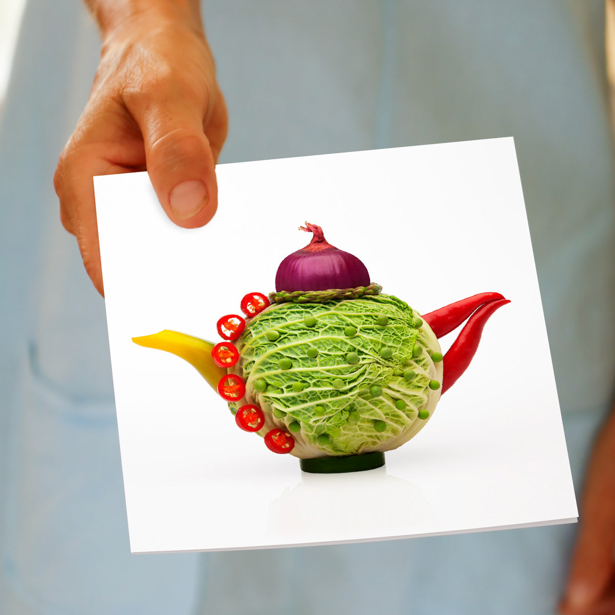 A model holding a fun cabbage teapot greeting card on a white background. A quality square greeting card from Golly Gosh Creations.