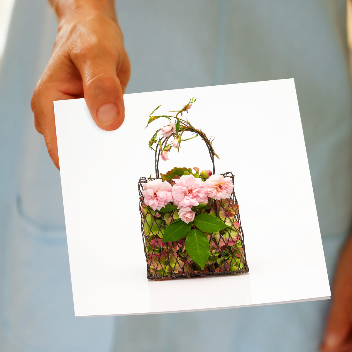 A model holding a pretty cecile brunner rose bag greeting card, on a white background. Size Size 142 x 142mm. Available from Golly Gosh Creations.