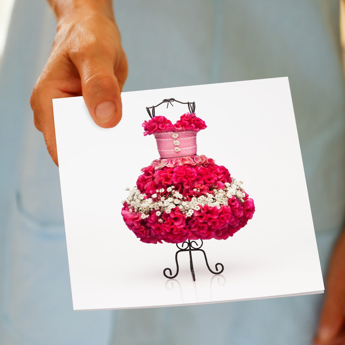 A model holding a vibrant pink celosia dress greeting card from Golly Gosh Creations. This is a quality square card. Size 142 x 142 mm.