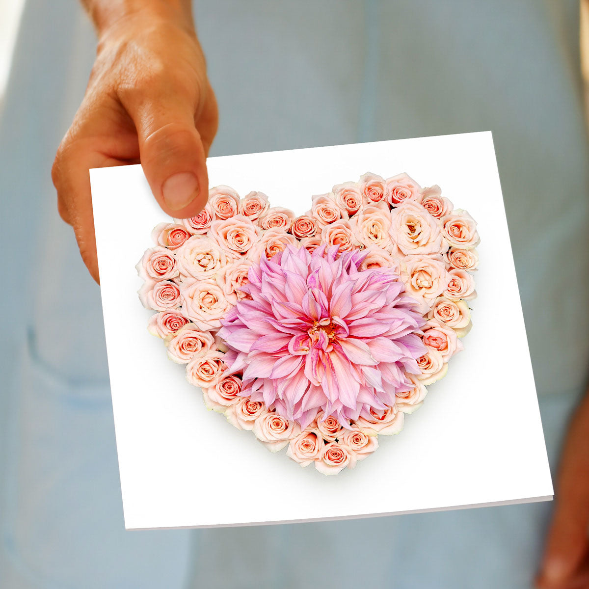 A beautiful pink dahlia heart greeting card, being hand held by a model. Found at Golly Gosh Creations. Size 142 x 142 mm
