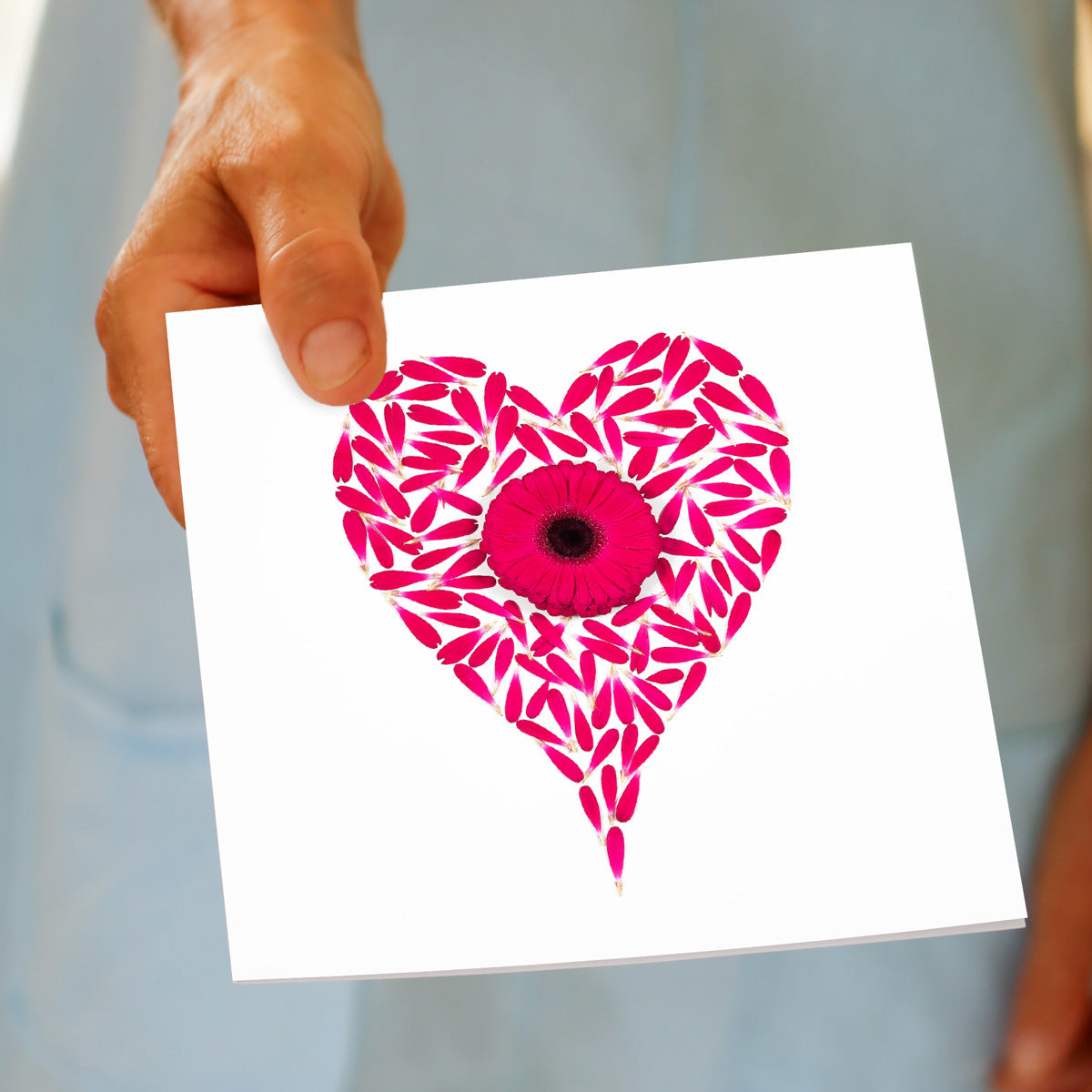 A hand held gerbera heart greeting card from Golly Gosh Creations. Created from vibrant pink gerbera petals and flower. Size 142 x 142 mm.
