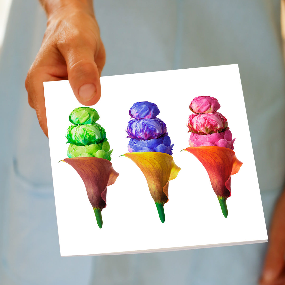 Hand displaying Peony Ice Cream Trio greeting card with three colorful floral arrangements resembling ice cream cones in green, purple, and pink.