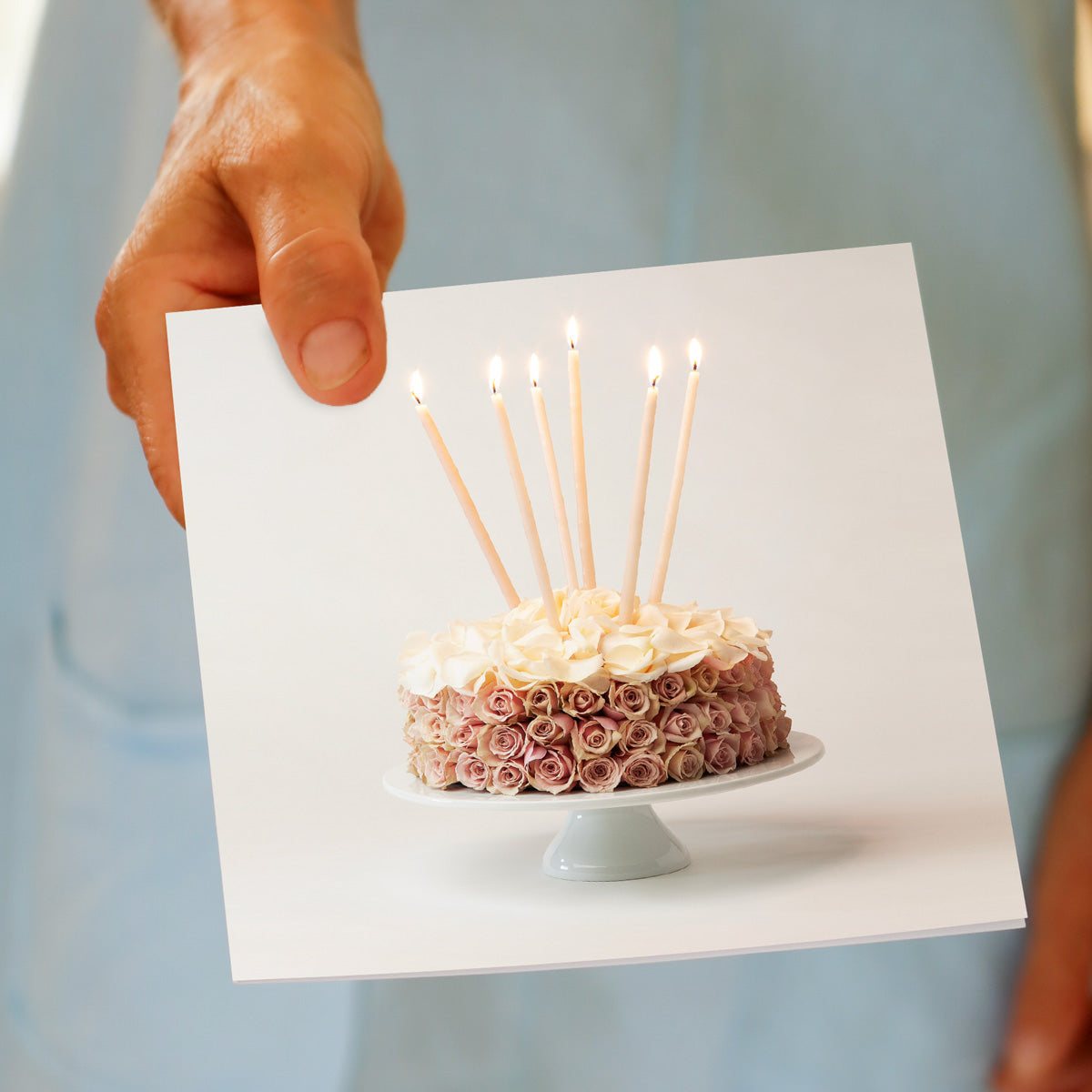 A hand held rose cake greeting card from Golly Gosh Creations. Crafted from soft pink roses with a topping of cream rose petals. Size 142 x 142 mm.