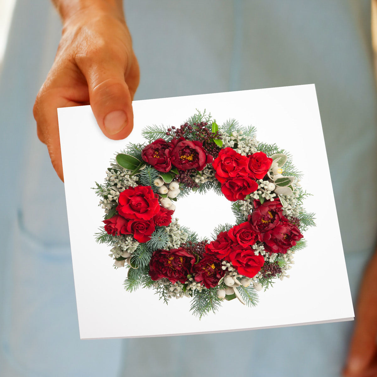 A pretty flower wreath from fresh flowers on a white background being hand held. Size 142 x 142mm. A quality greeting card found at Golly Gosh Creations.