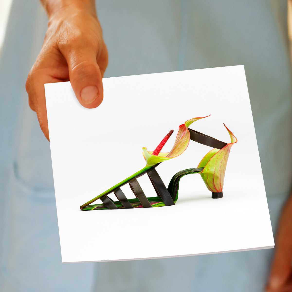 A model holding a anthurium flower sandal greeting card from Golly Gosh Creations. Created from fresh flower on a white background.