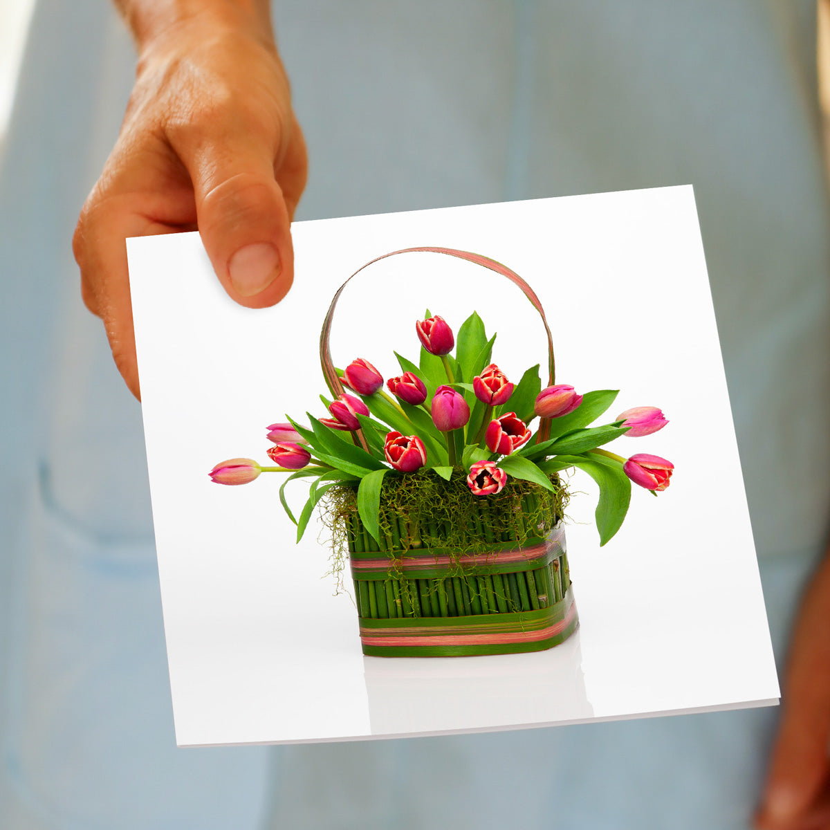 A pretty arrangement of pink tulips in a floral carry box on a white background greeting card, being held by hand. A quality greeting card found at Golly Gosh Creations.