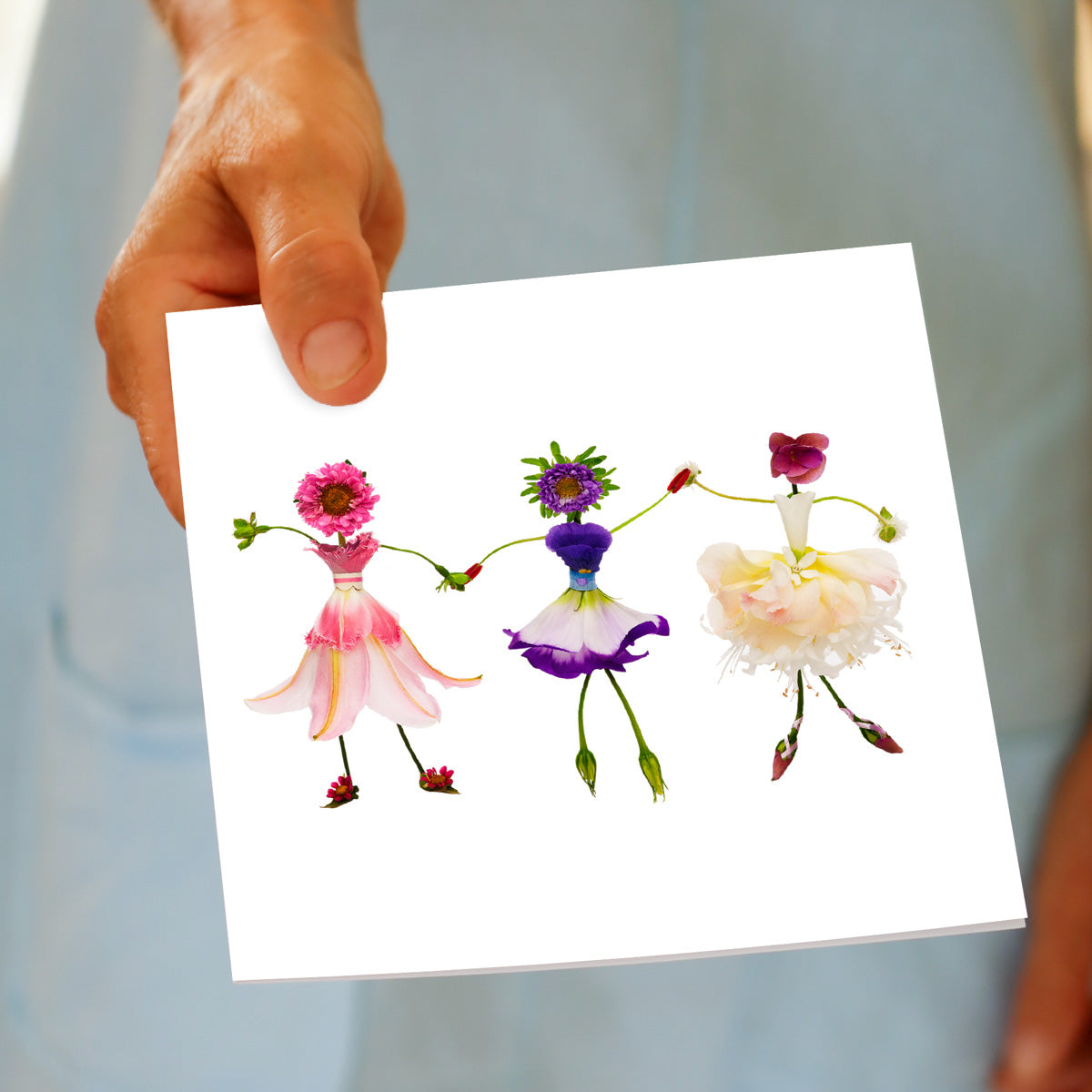 A charming dancing girls greeting card being hand held. Delicate ballerinas crafted from fresh blooms. Found at Golly Gosh Creations. Size 142 x 142 mm