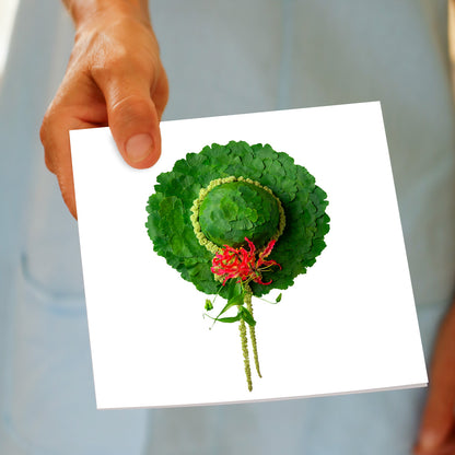 A quirky ginkgo hat square greeting card being held by hand, from Golly Gosh Creations. Crafted from lush green fan shaped ginkgo leaves.