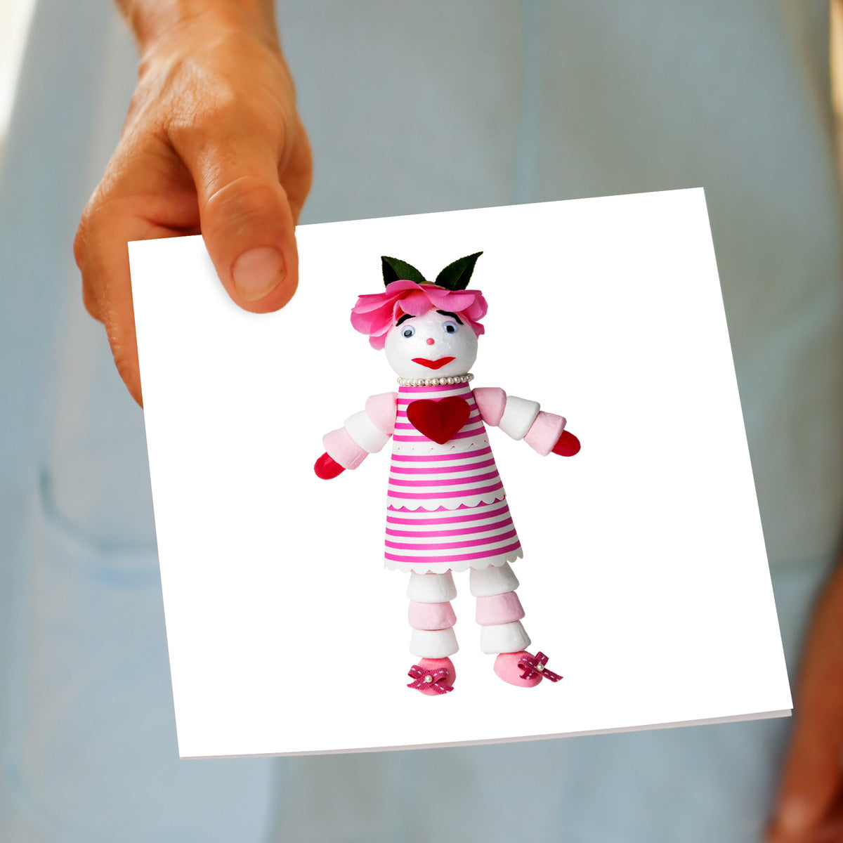 A marshmallow doll greeting card being held by hand from Golly Gosh Creations.
A generous square card created from an assortment of marshmallows.