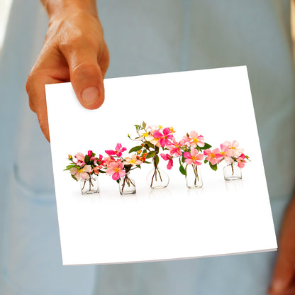 A pink rose vases greeting card from Golly Gosh Creations being held by hand. A pretty arrangement of dainty pink roses in vases. Size 142 x 142 mm.