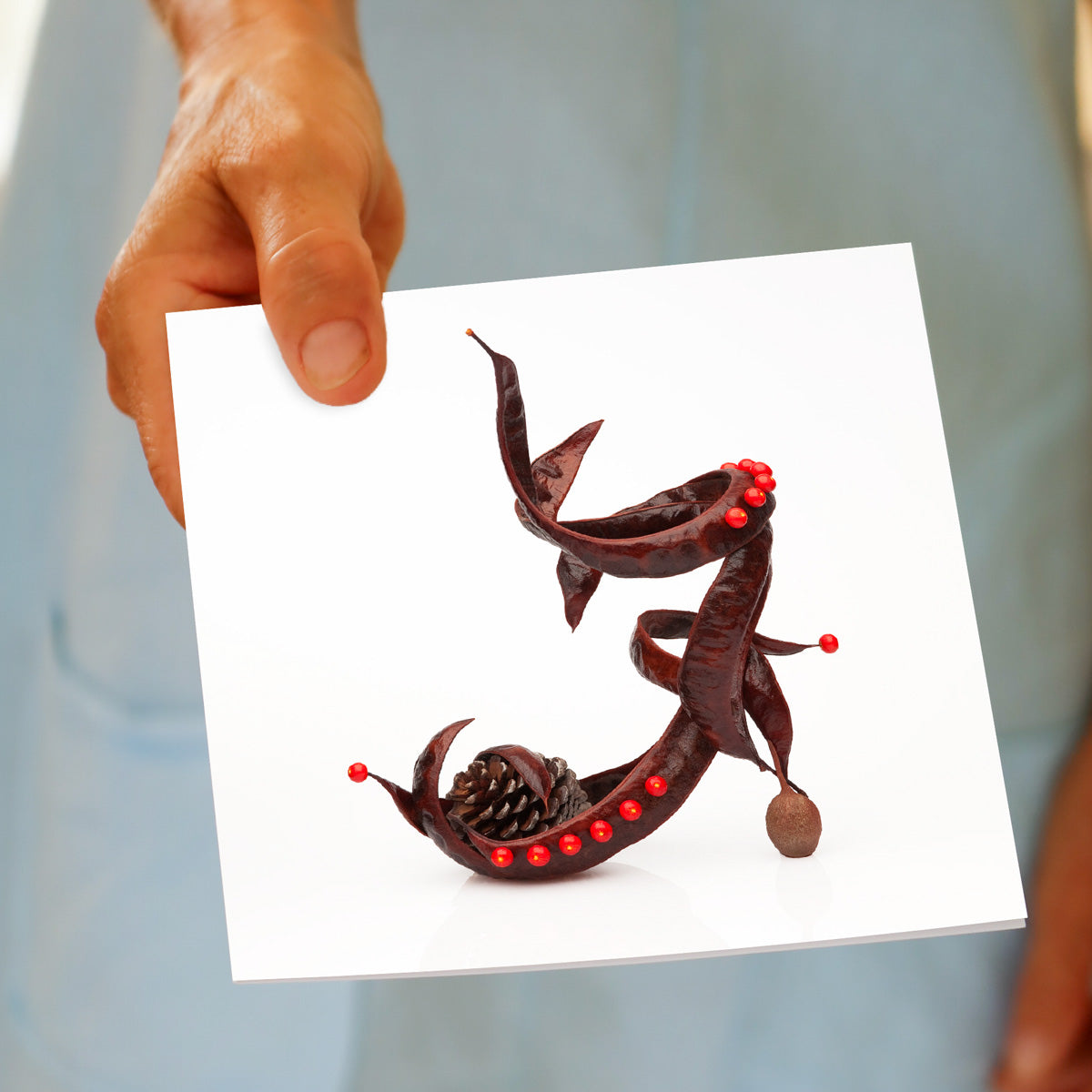 A hand held pod sandal greeting card from Golly Gosh Creations. This generous square card is crafted from brown autumn pods with a twist of red buds.