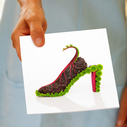A red beet shoe greeting card by Golly Gosh Creations being hand held. Created from stunning red beet leaves and dainty green flowers. Size 142 x 142 mm.