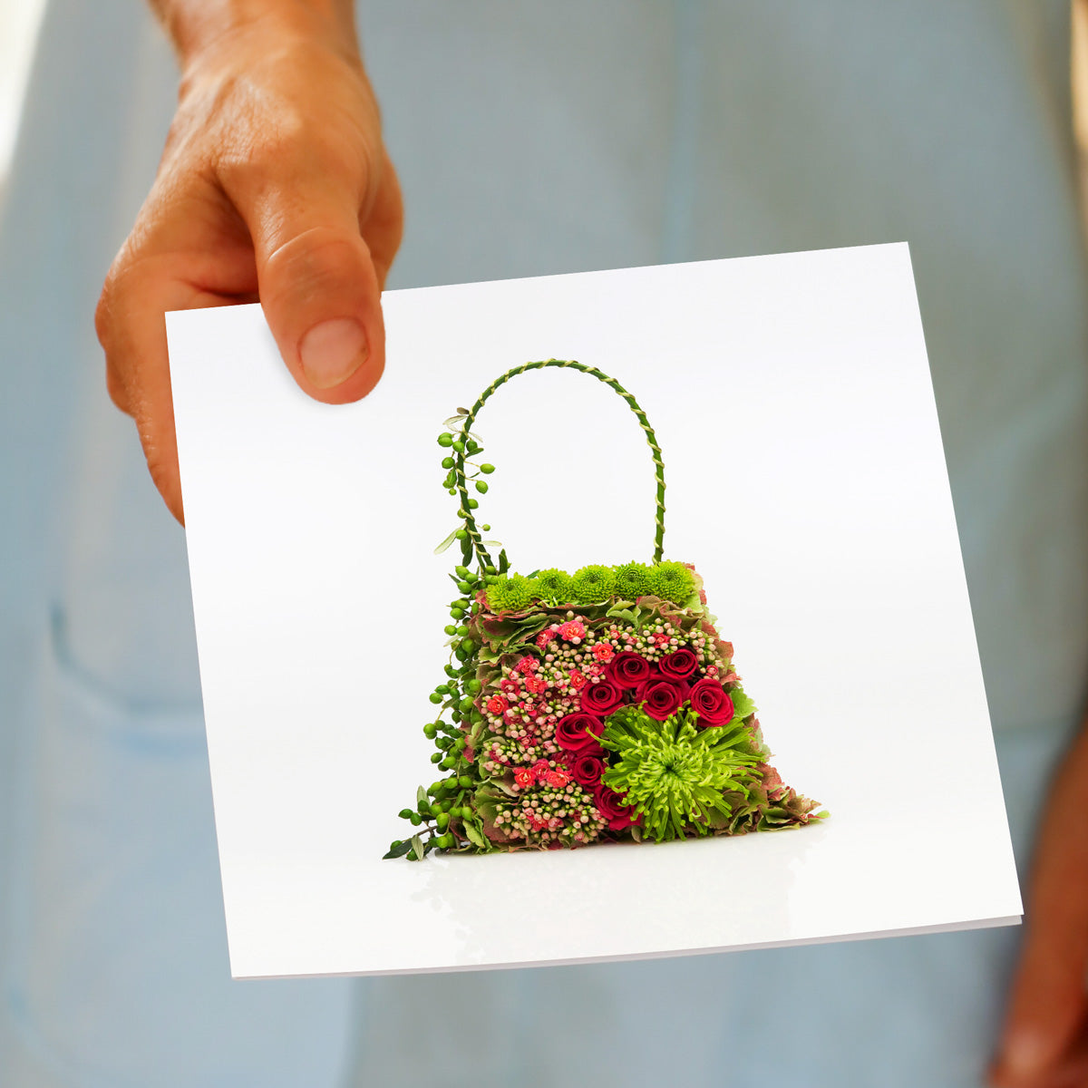 A tapestrty bag greeting card from Golly Gosh Creations. Size 142 x 142 mm. Created from lush green and red flowers and blooms.
